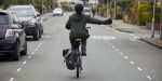Bikeability Trust Rolls Out Online Course to Boost Adult Riders' Confidence Adult cyclist riding confidently on a road with a laptop showing an online training course overlay