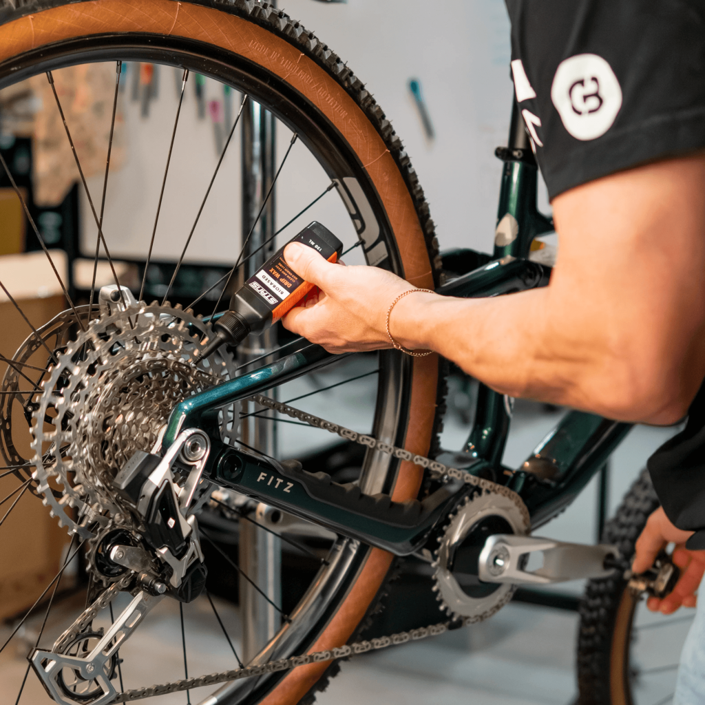 Bottle of Stan's Polar Drip Wax chain lubricant beside a bicycle chain